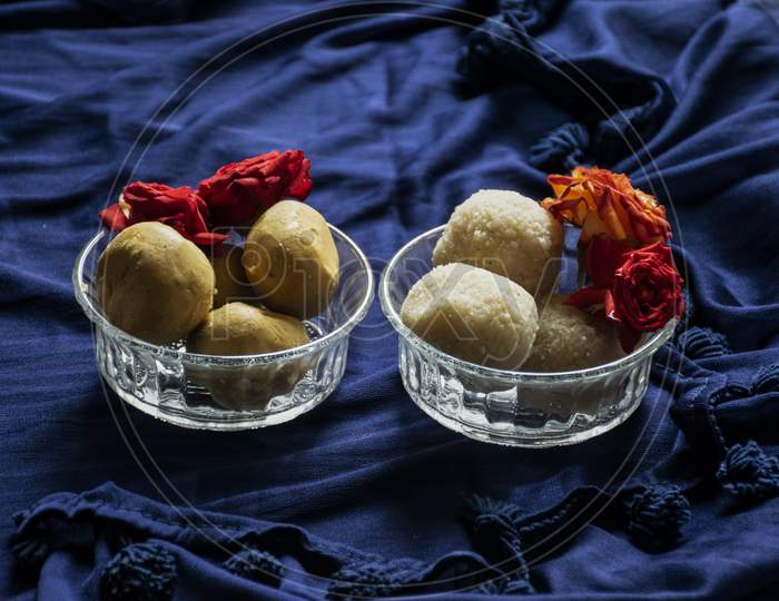 Picture Of Delicious Besan Laddu And Rawa Laddu Decorated In Bowl With Fresh Red Roses In A Blue Background. Besan Laddus And Rawa Laddu Made During Diwali Festival In India