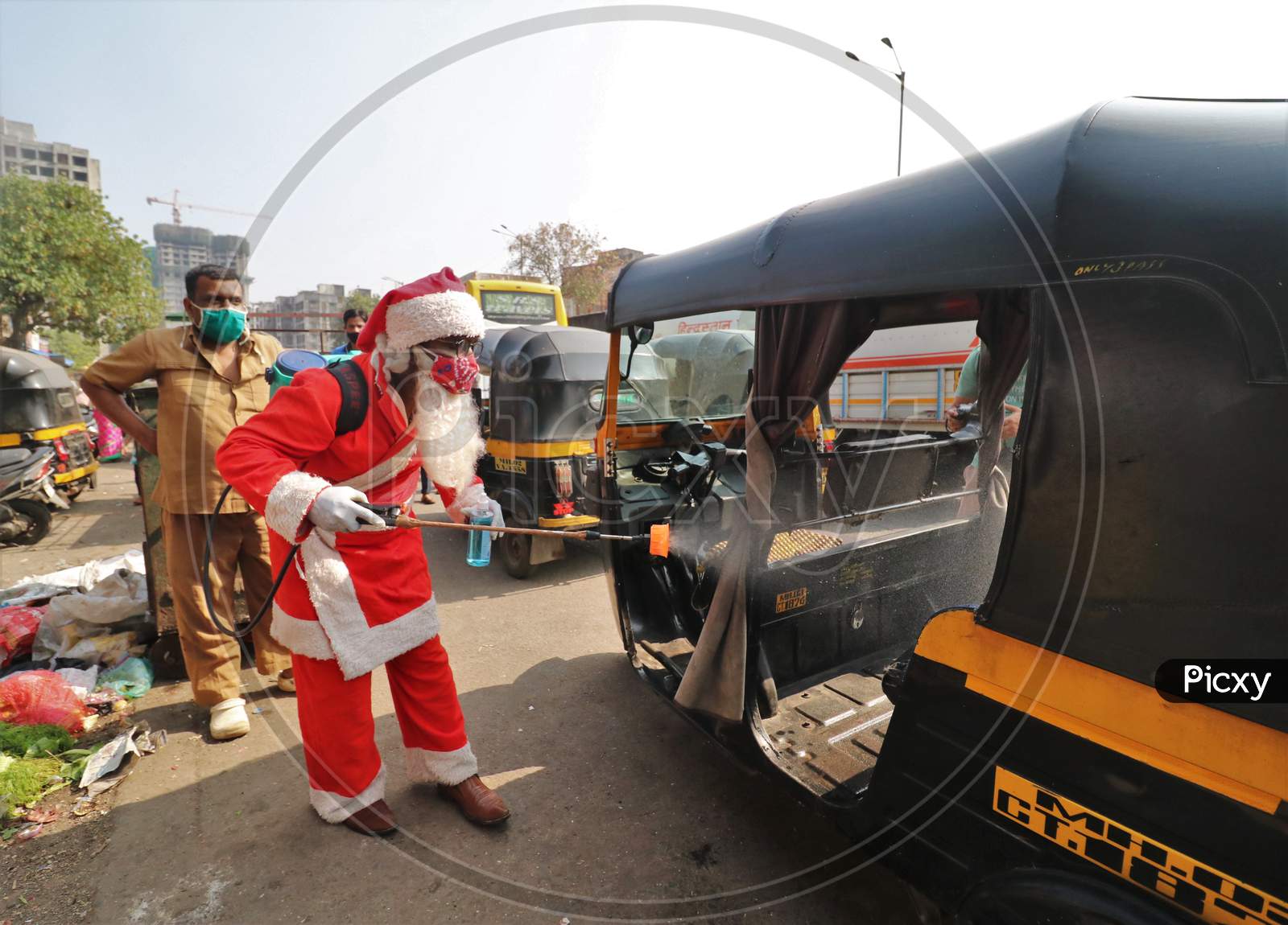 A man wearing a Santa Claus costume sanitizes an auto rickshaw, amidst the spread of the coronavirus disease (COVID-19), in Mumbai, India, December, 2020.