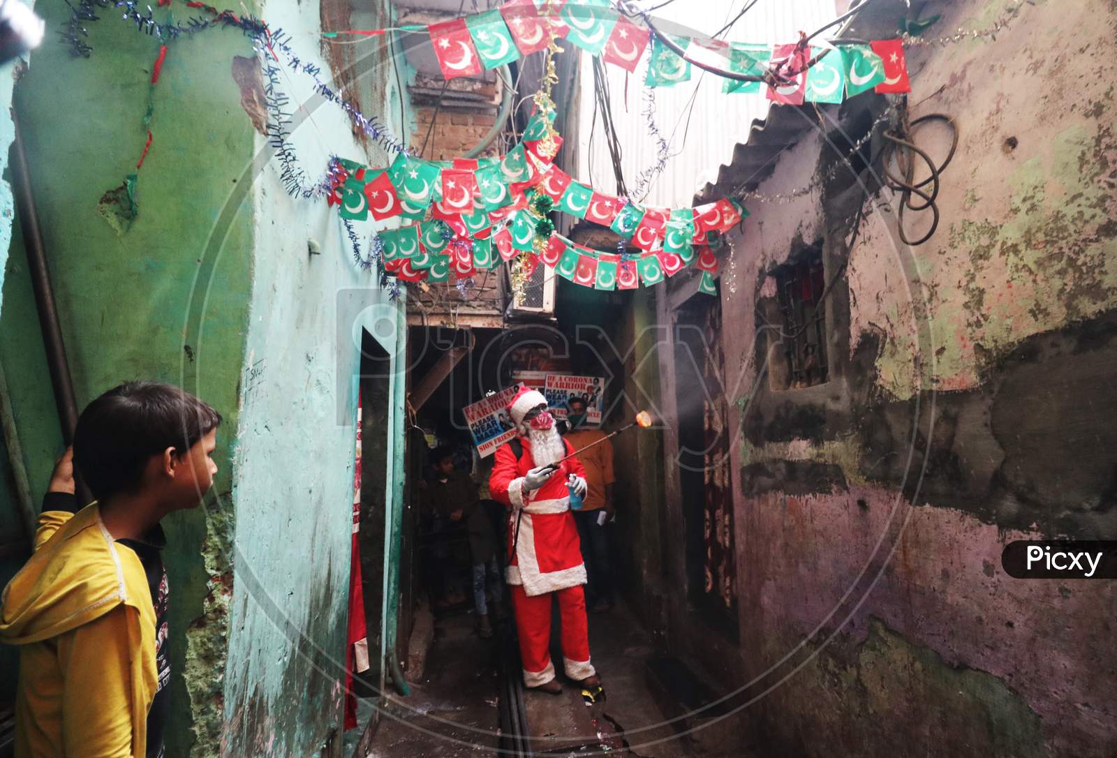A man wearing a Santa Claus costume sanitizes the entrance of a house inside a slum, amidst the spread of the coronavirus disease (COVID-19), in Mumbai, India, December, 2020.