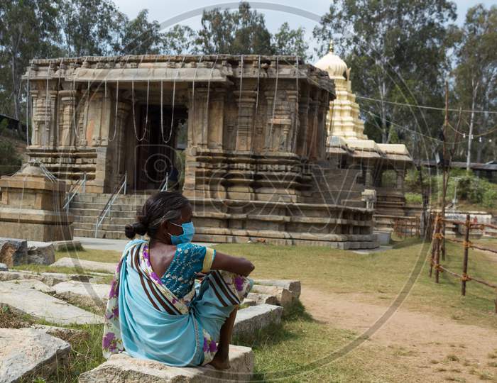 An Homeless poor lady is seen sitting in front of the Shiva temple to collect alms from the pilgrims visiting in Talakadu during Kumba mela near Mysuru,India.