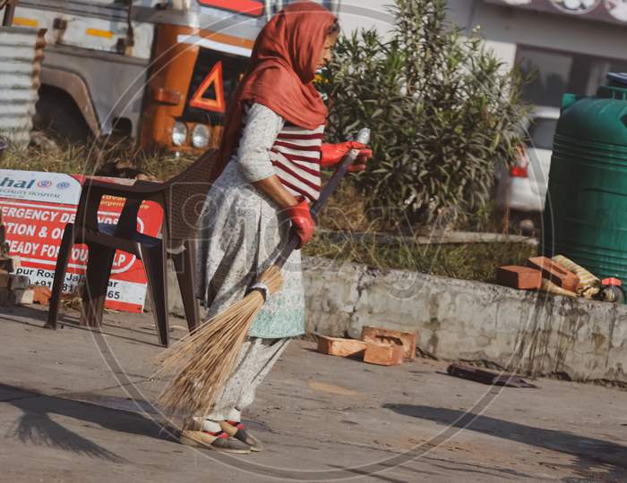 women worker  cleaning the street with broom
