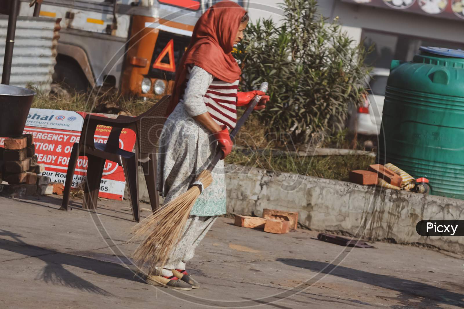 women worker  cleaning the street with broom