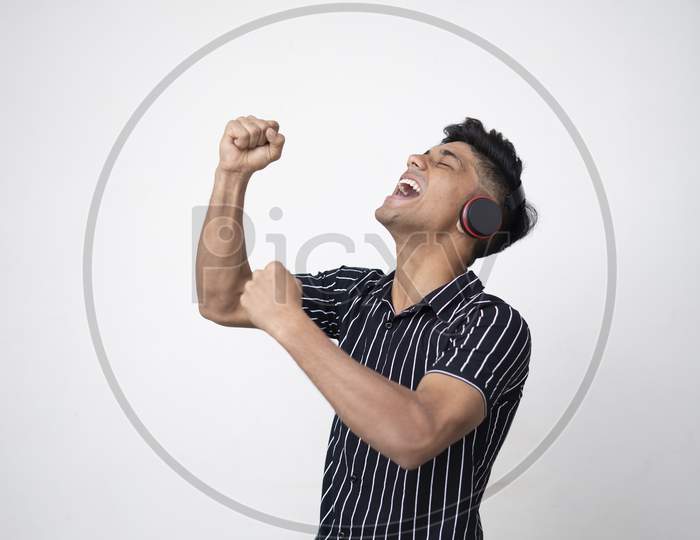 Young Indian Handsome Man Both Hand In Air Listen To Music In Wireless Headphone. Concept Of Emotions , Expression
