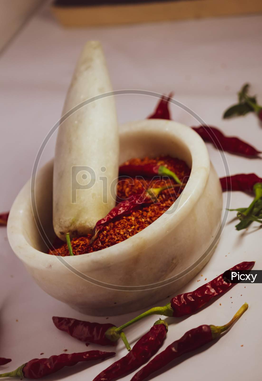 Dry red chillies and flakes powder in motor pestle