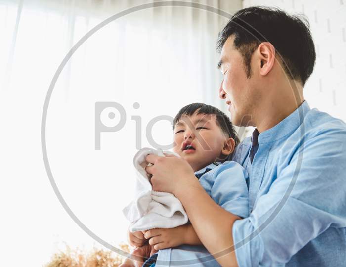 Asian Japanese Father Consoling His Crying Son And Wiping Tears In Bedroom At His Home White Curtain Background. People Lifestyle Health. Medical And Health Concept. Negative Emotion Theme.