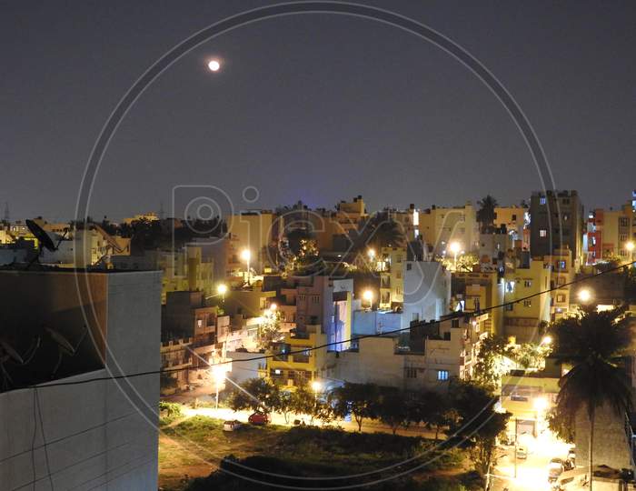 Bangalore Cityscape View At Night With Full Moon And Building Lights Are Glowing