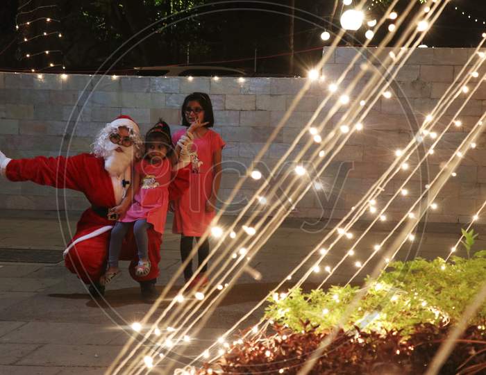 A woman dressed as Santa Claus poses for a picture with kids at a residential area on Christmas eve in Mumbai, India, December 24, 2020.