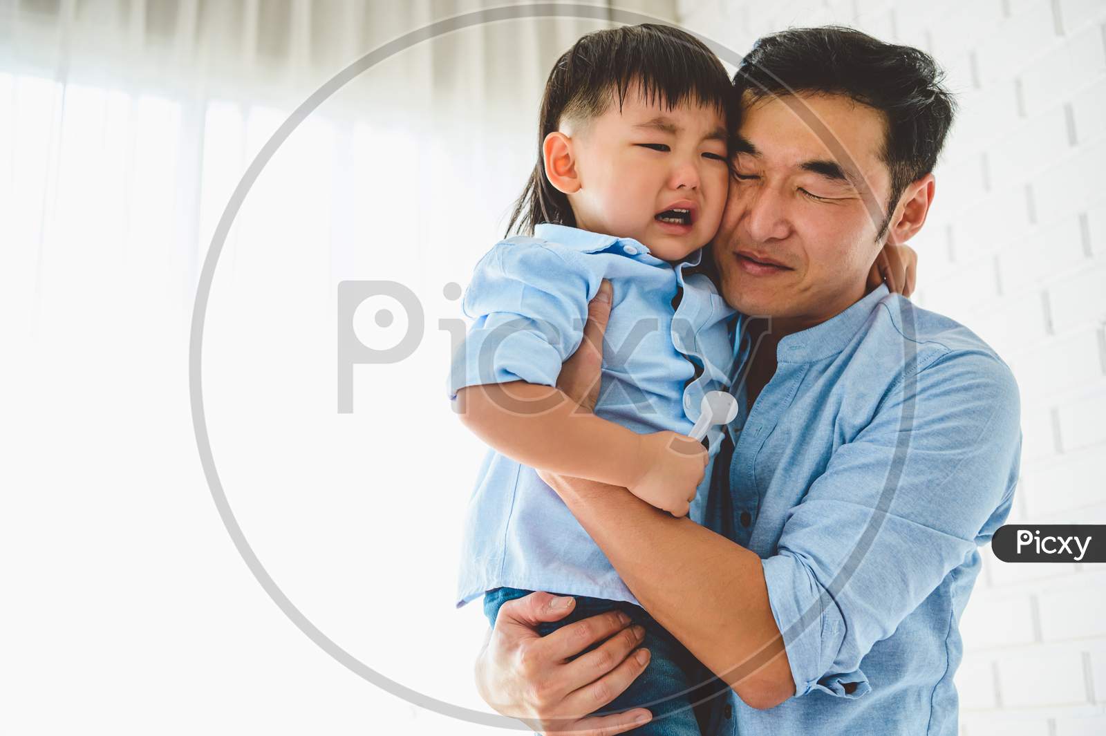 Asian Japanese Father Carrying And Consoling His Crying Son In Bedroom At His Home With Window And White Curtain Background. People Lifestyle Health. Quarantine In Covid-19 Or Coranavirus Epidemic