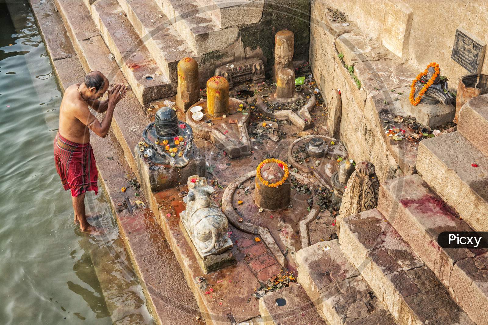 Man Offers Water To The Ganges As Part Of A Morning Prayer Ritual At The Ganges River Ghat At Varanasi, India