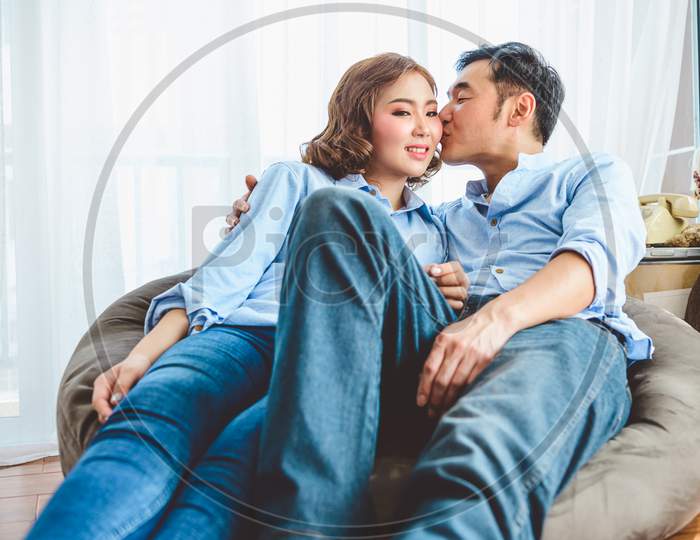 Asian Couple Having Kissing Romance On Sofa In Living Room Domestic House In Valentines Day. Lifestyle And Happiness Family Concept.