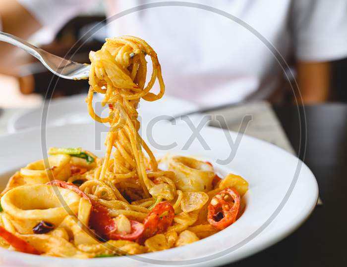 Woman Eating Seafood Spaghetti White Sauce With A Fork At Italian Restaurant. Food And Cuisine Concept.