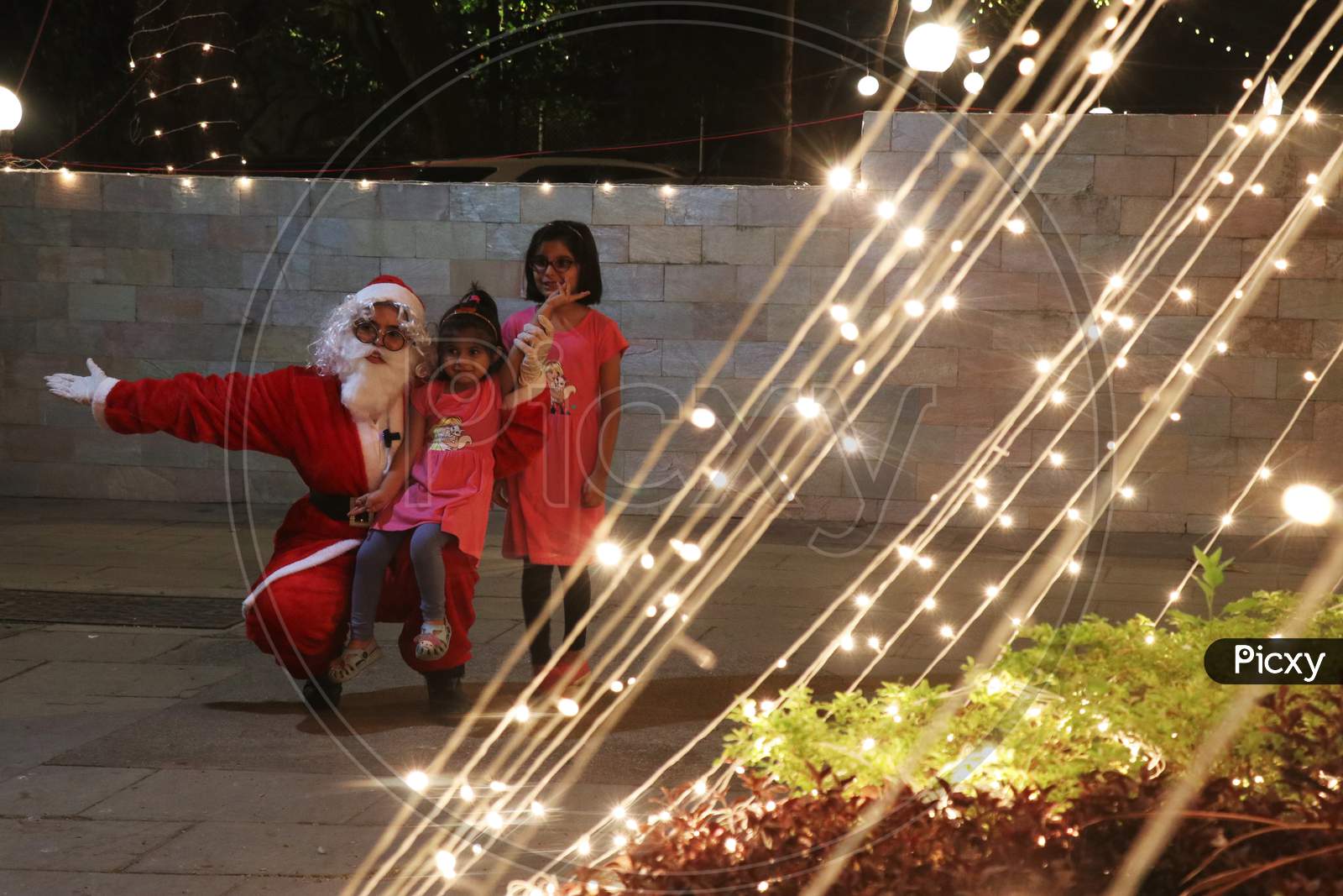 A woman dressed as Santa Claus poses for a picture with kids at a residential area on Christmas eve in Mumbai, India, December 24, 2020.