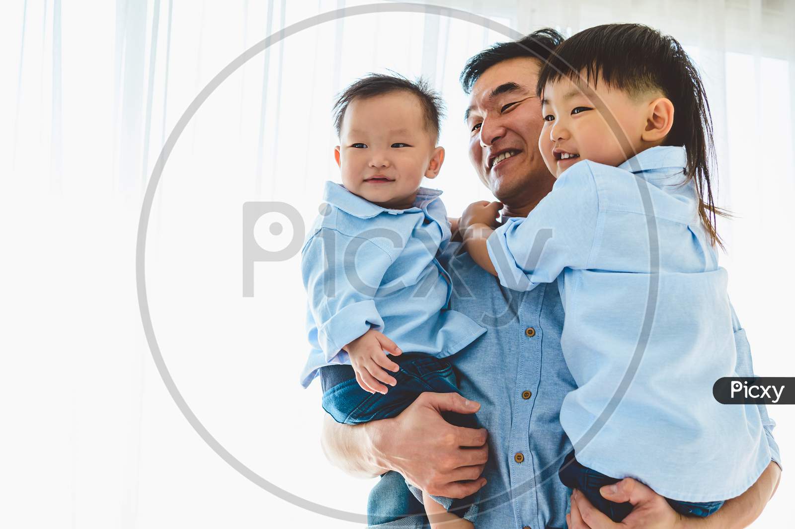 Happy Father Carrying Two Children In Bedroom At Their House. Family Living And Having Positive Expression Emotion Togetherness. Leisure Time. People Lifestyle Health. Quarantine Covid-19 Coranavirus