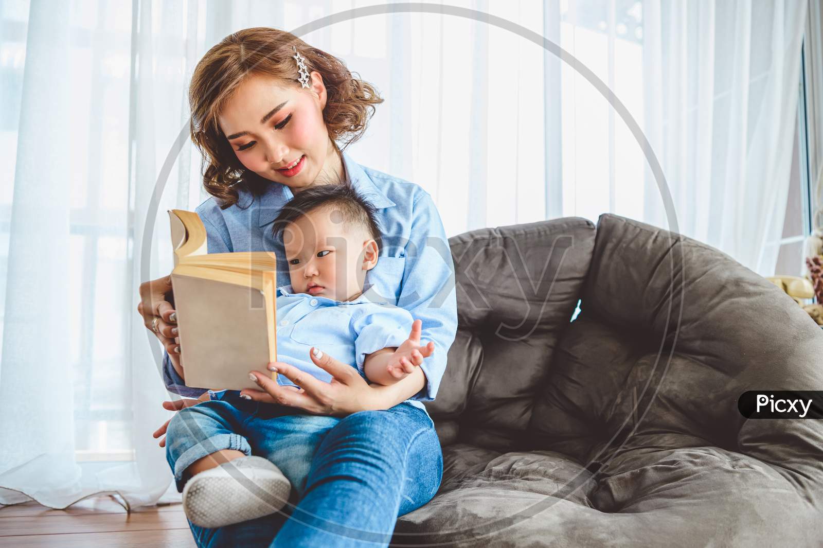 Asian Mother Reading With Her Son In The Living Room At Home. People Lifestyle And Leisure Activity. Kids And Baby Concept
