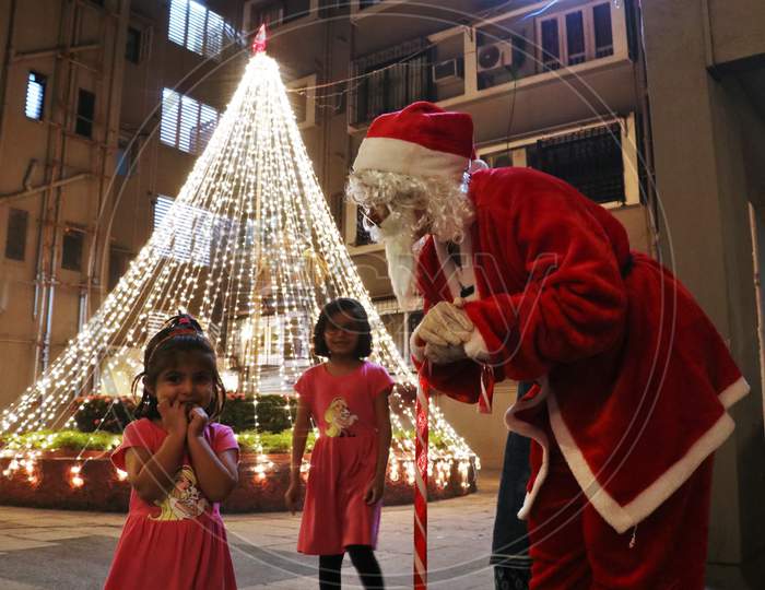 A woman dressed as Santa Claus interacts with kids at a residential area on Christmas eve in Mumbai, India, December 24, 2020.