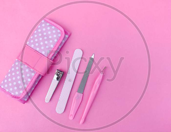 Set Of Pink Color Manicure Tools And Pink Pouch Isolated On Pink Background. Copyspace