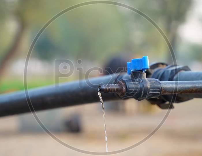 Water Dropping View From Blue Water Valve With Blurred Background. Closeup View Of Water Leak From Iron Pipe. Save Water Concept.