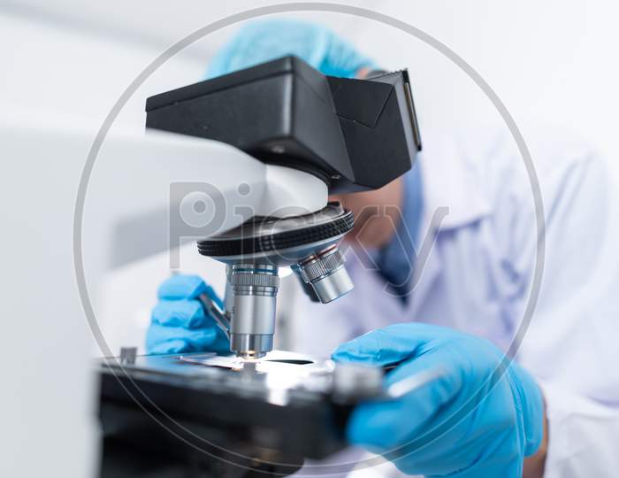 Scientists studying a virus ,looking through microscope.Scientists in protective suits in a science laboratory study a virus. covid19 blood test