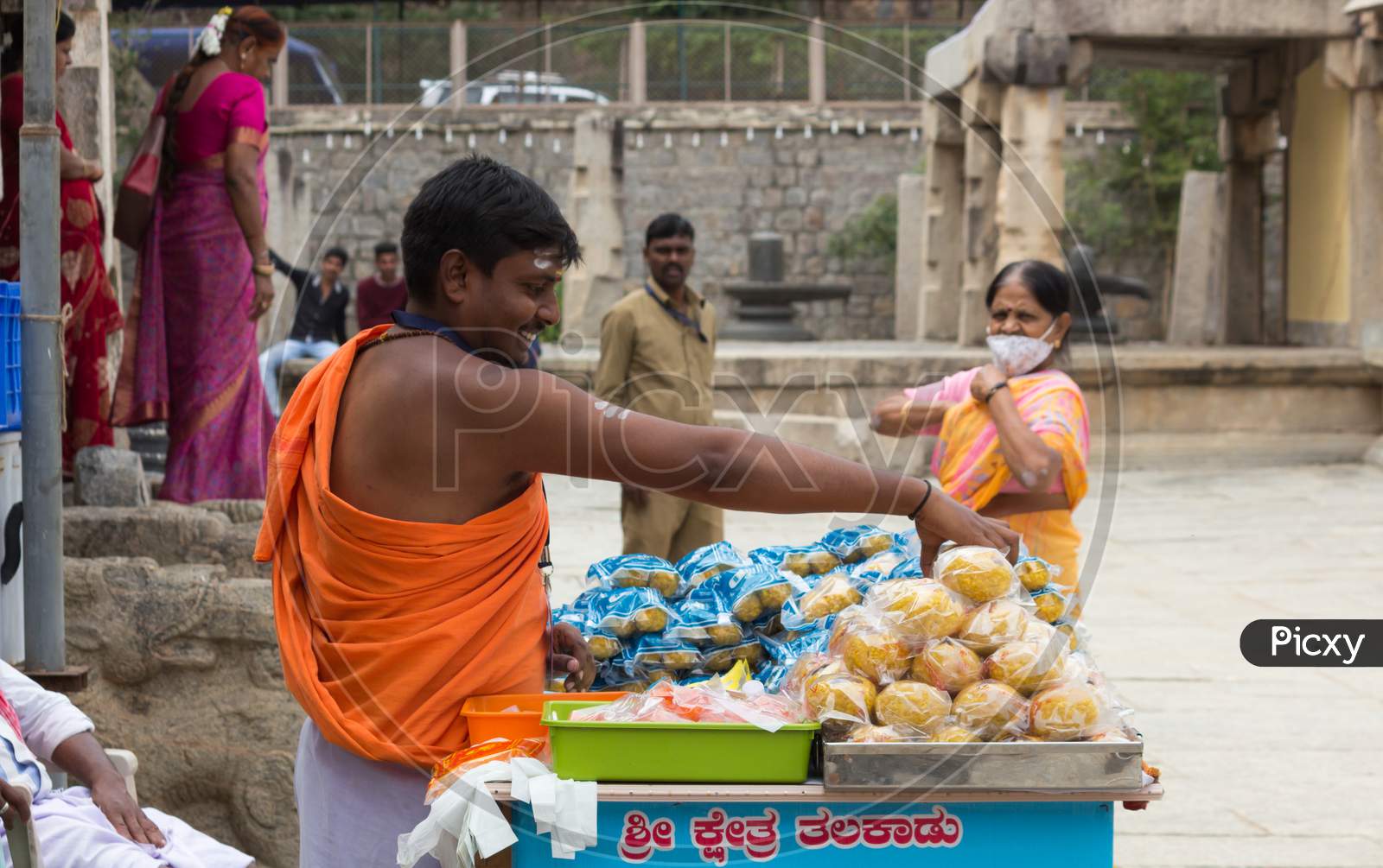 A Hindu Priest is seen selling Sweets and souvenirs for the pilgrims visiting the Shiva temple in Talakadu village near Mysuru in India.