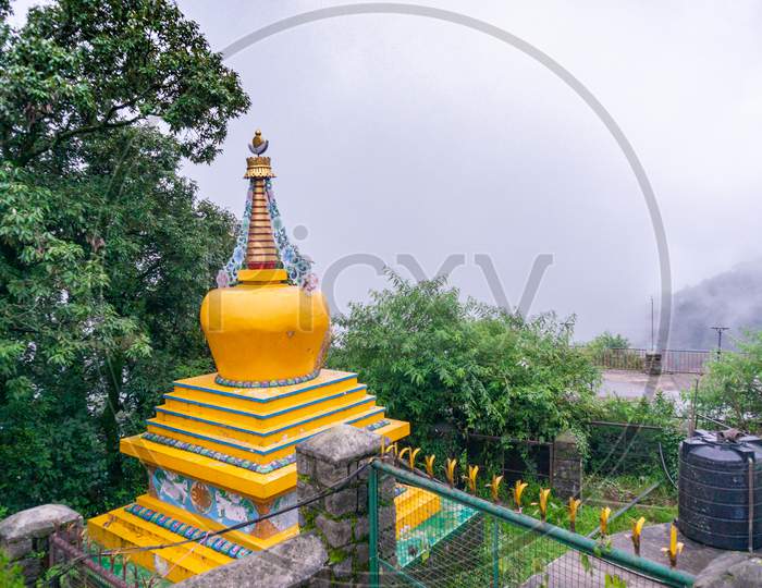 Yellow Temple Spire Dome Building Perched In The Middle Of Trees Looking Over A Cloudy Foggy Valley In A Hillstation Like Mcleodganj Shimla And More A Popular Tourist And Homestay Destination