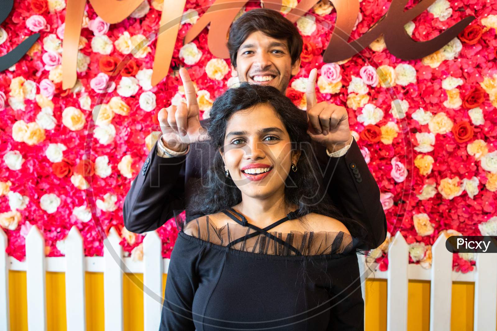 Young Happy Cheerful Indian Couple In Love Have Fun Indoor Against Floral Background, Boyfriend Girlfriend Relationship, New Year Or Valentines Day.