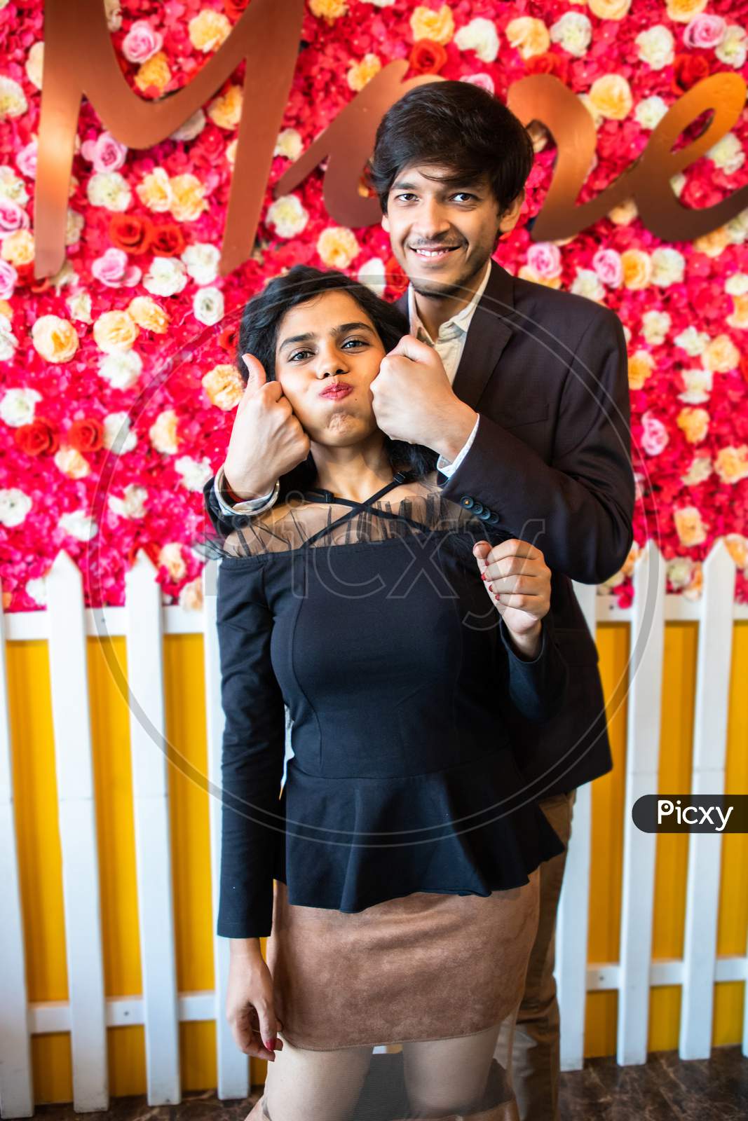 Young Happy Cheerful Indian Couple In Love Have Fun Indoor Against Floral Background, Boyfriend Girlfriend Relationship, New Year Or Valentines Day.