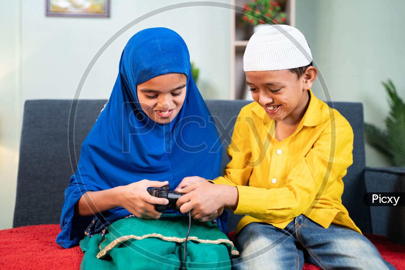 Muslim Brother Snatching Gamepad From His Sister To Play Video Game At Home - Concept Of Childhood Sibling Fighting
