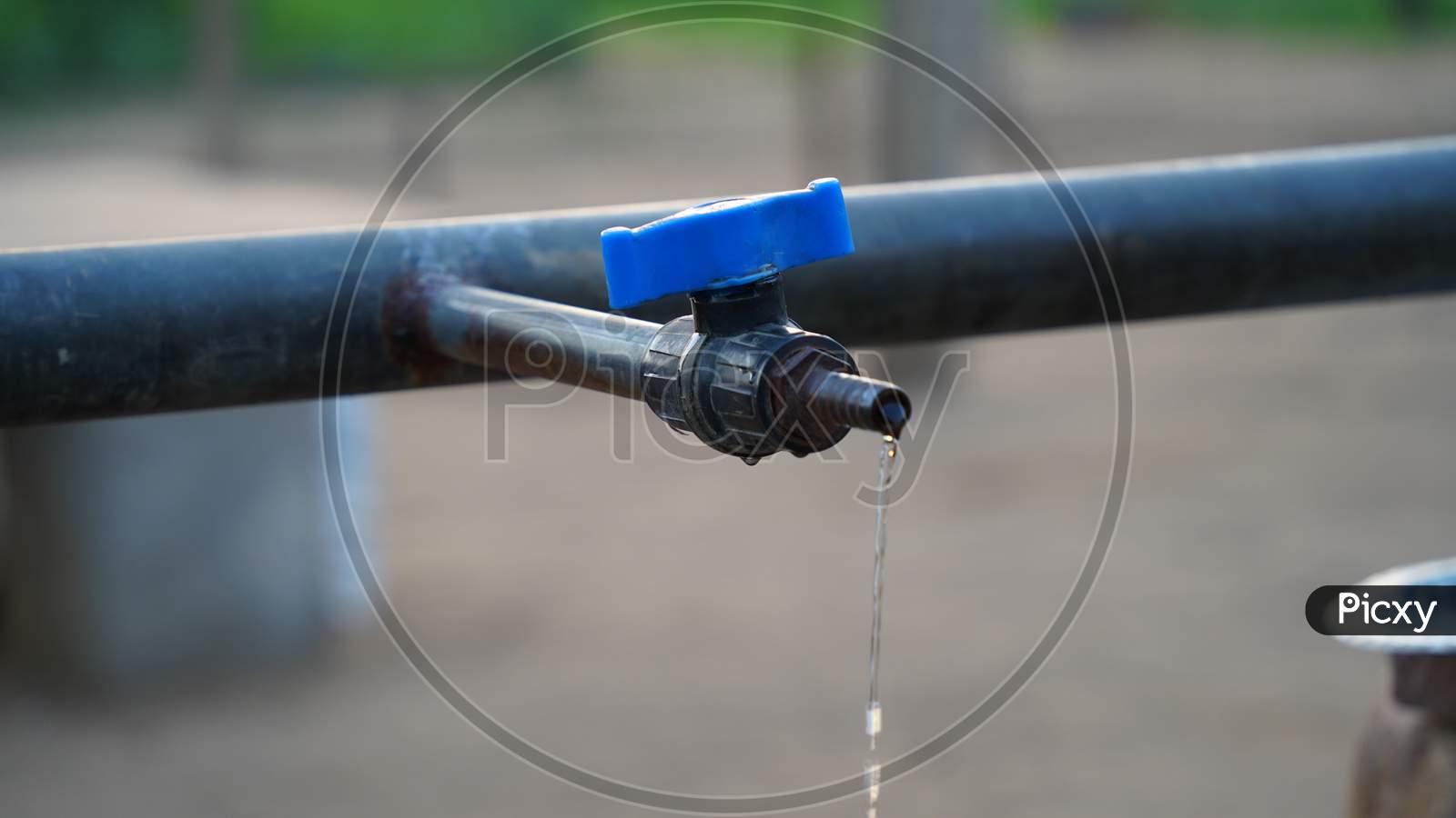 Selective Focus On Water Dropping From Blue Water Tap. Regular Flowing Water From Blue Faucet. Save Water Concept.