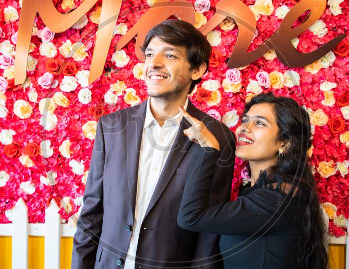 Young Happy Cheerful Indian Couple In Love Have Fun Indoor Against Flower Background, Boyfriend Girlfriend Relationship, New Year Or Valentines Day.