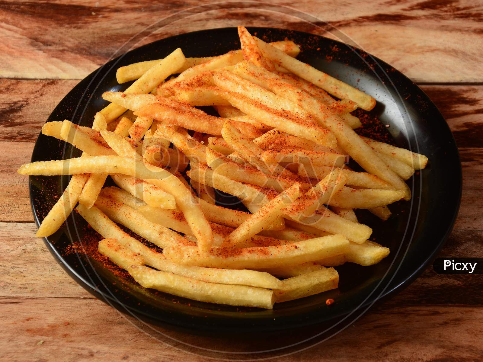 Image Of Tasty Spicy Peri Peri French Fries Served In A Plate Over A Rustic Wooden Background