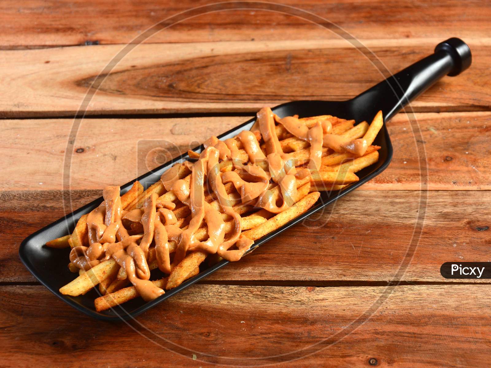 French Fries Topped With Masala Flavored Cheese, Served In A Plate Over A Rustic Wooden Background, Selective Focus