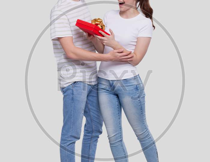 Man Makes A Present For Girl. Surprise Gift For Girl. Young Man Having A Present For His Girlfriend. Christmas, New Year, Birthday, Valentines Gift Concept