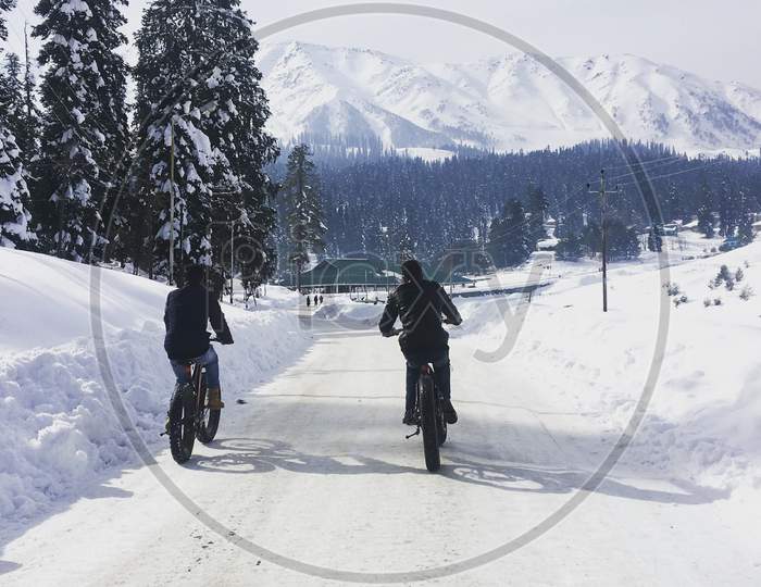 2 boys riding bicycle on snow in Gulmarg Kashmir