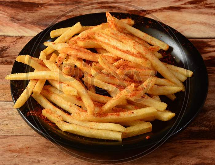 Tasty Spicy Peri Peri French Fries Served In A Plate Over A Rustic Wooden Background, Selective Focus