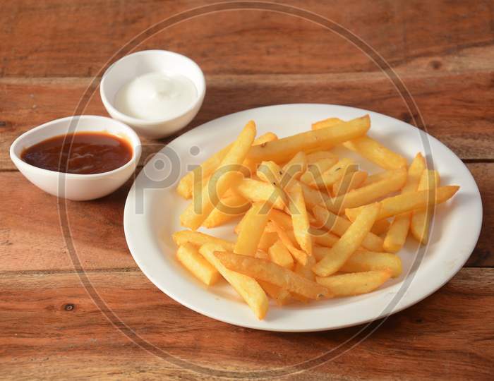 Golden Fried French Fries With Tomato Ketchup And Mayonnaise Served In A Plate Over A Rustic Wooden Background, Selective Focus