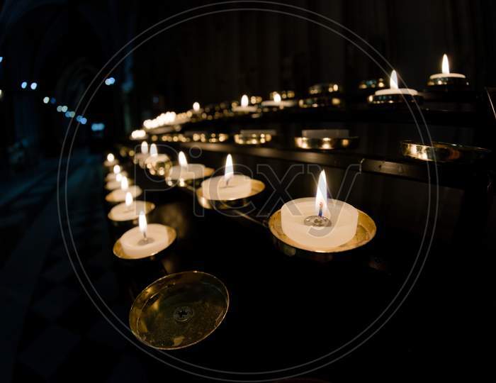 Prayer Candles Shine Bright In A Dark Cathedral, From The Other Side.