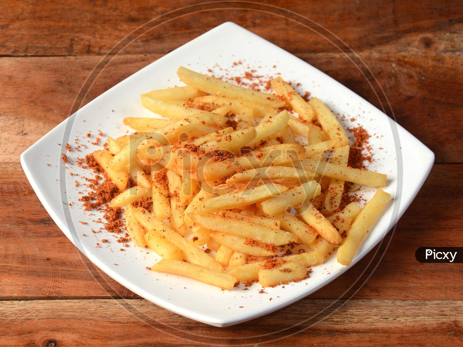 Tasty Spicy Peri Peri French Fries Served In A Plate Over A Rustic Wooden Background, Selective Focus