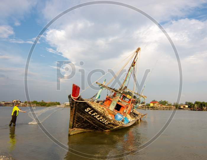 A Fisherman Cast The Net Beside Fishing Boat