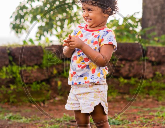 Playful Pretty Indian girl child/infant playing outdoors with nice environmental background