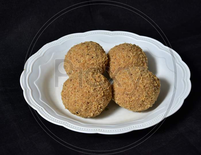 Churma laddu or laddoo arranged in circular pattern in white plates plastic, churma ladu.