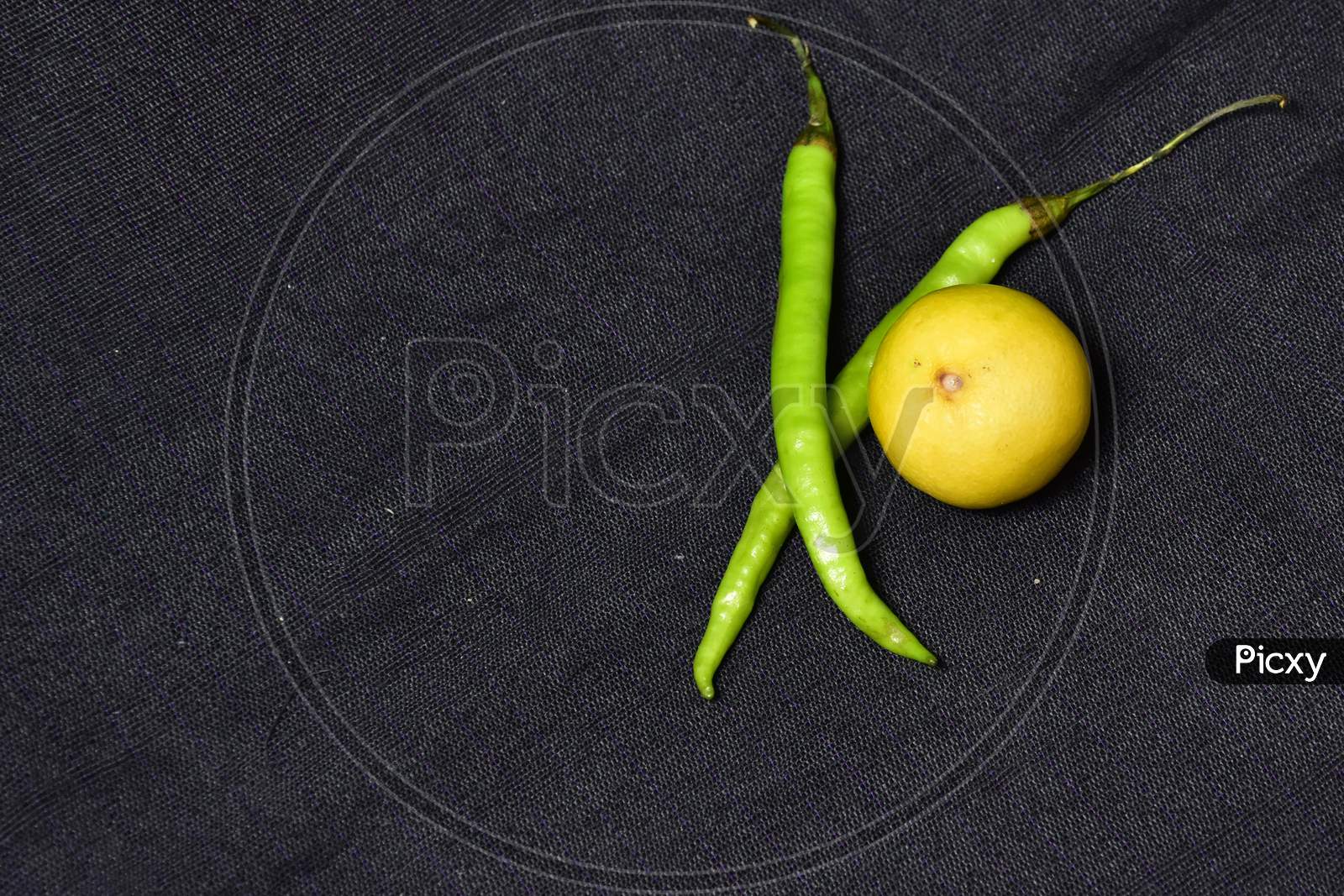Fresh green pepper with yellow and green lemon on a black fabric, top view, fresh green pepper healthy and useful food