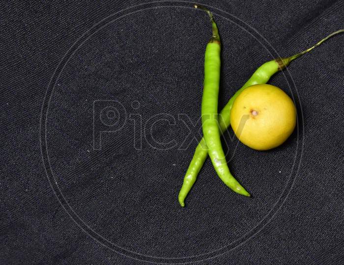 Fresh green pepper with yellow and green lemon on a black fabric, top view, fresh green pepper healthy and useful food