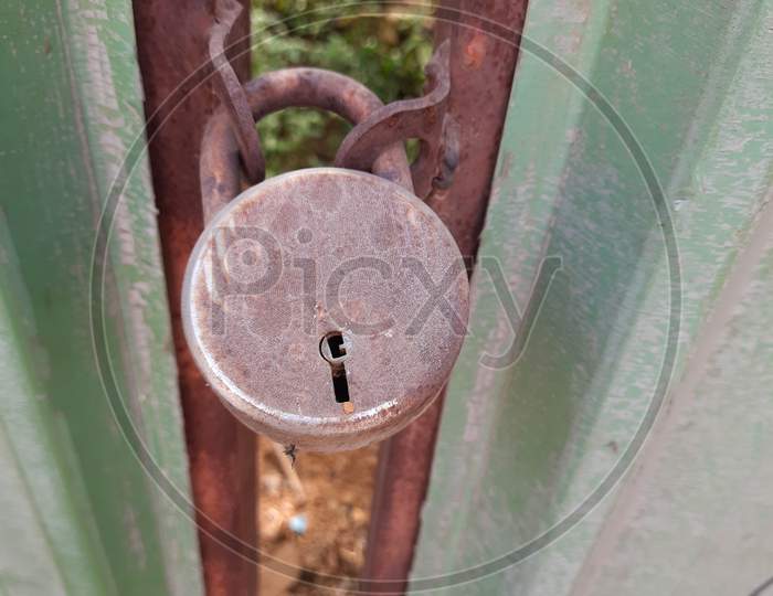 Gate is locked with Steel or Iron Rusted lock in a empty space or field inside