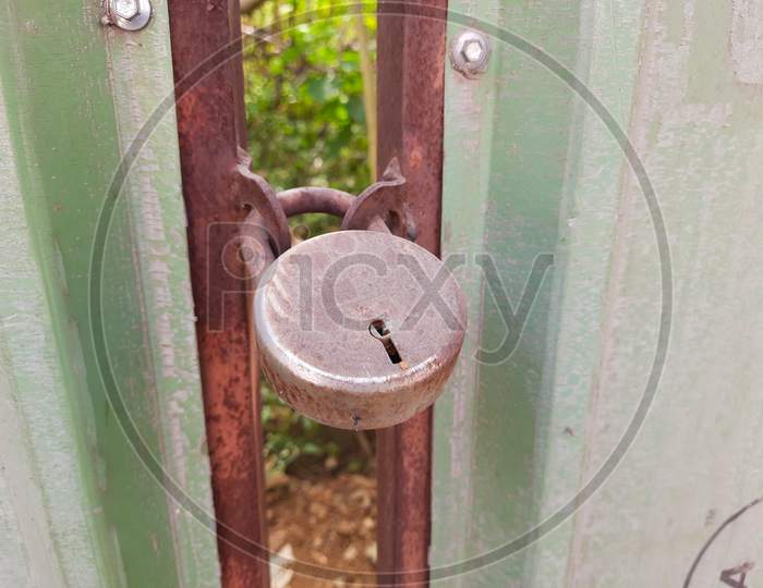 Gate is locked with Steel or Iron Rusted lock in a empty space or field inside