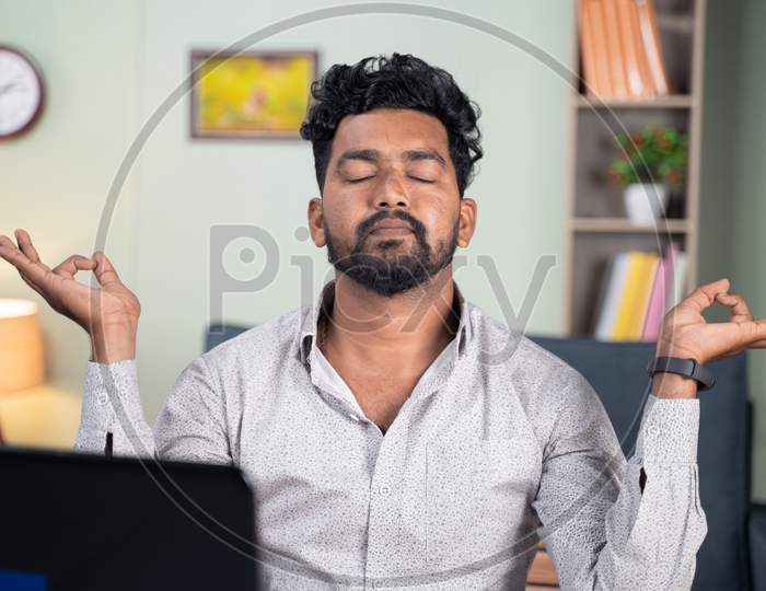 Young Man Meditating At Home Due To Work Pressure Or Stress - Concept Of Taking Break, Relaxing, Peace Of Mind
