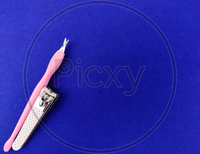 One Pink Color Nail Clipper And Manicure Tool Isolated On Blue Background. Copyspace