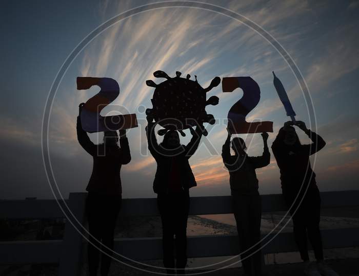 Young women hold coronavirus theme based cut-outs on the eve of New Year 2021, in Jammu on 31 Dec,2020.