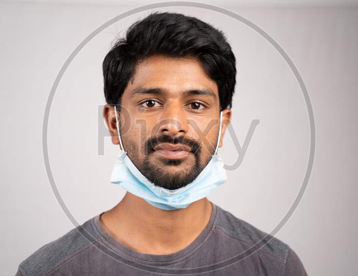 Young Man Wearing Medical Mask On Neck- Concept Showing Of Improper Way Of Using Face Masks During Coronavirus Or Covid-19 Crisis.