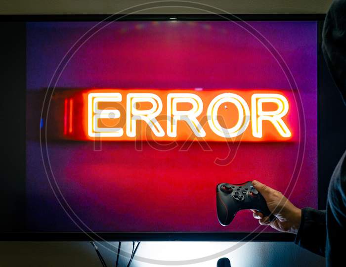 Man Holding A Controller In Front Of A Screen Showing An Error Message As A Game Crashes Due To Bugs In Unfinished Software