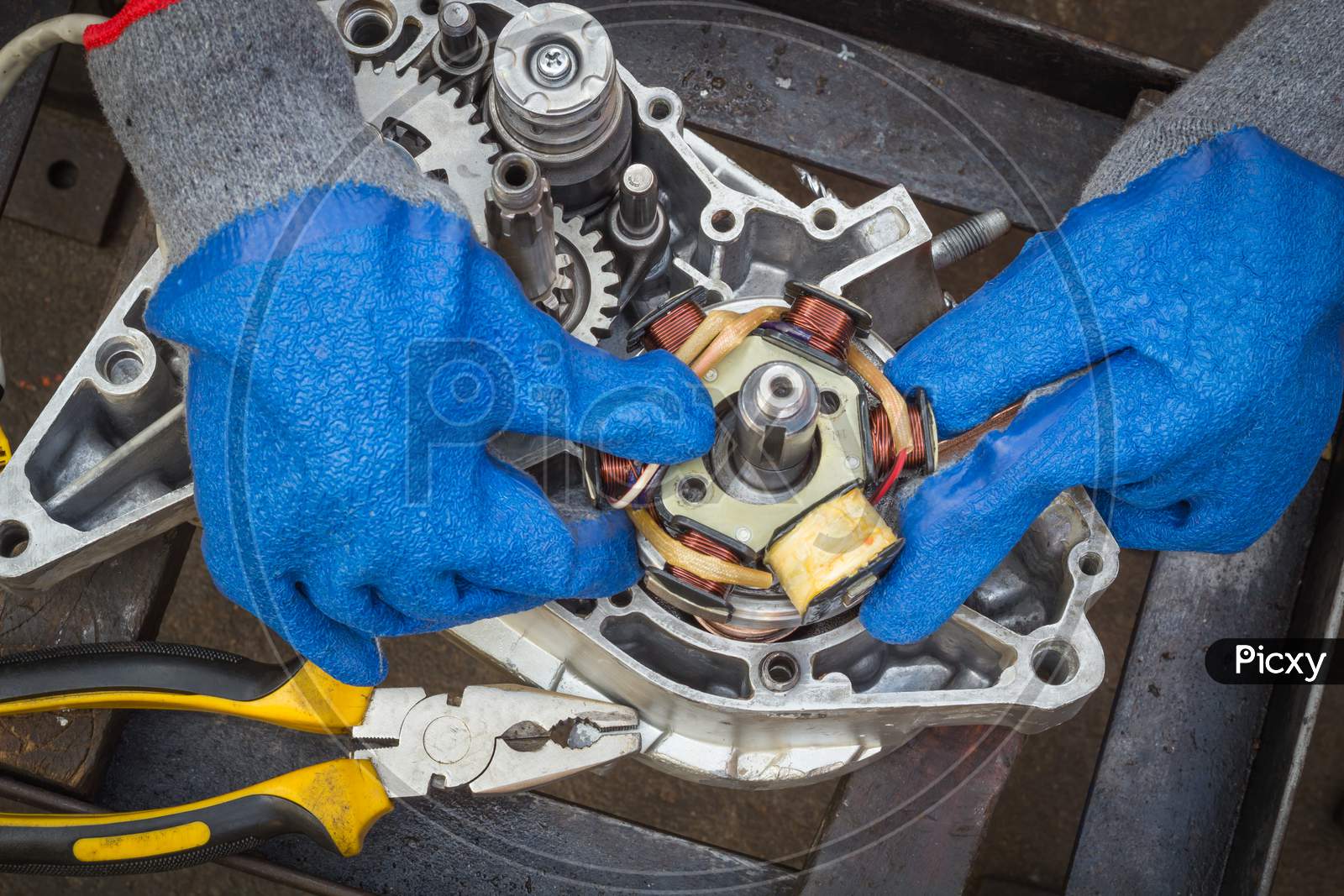 A Dexterous pair of hands is carefully assembling a Electrical stator coil plate inside a Motorcycle engine during an Overhauling procedure at Motorcycle workshop in Mysuru,India.